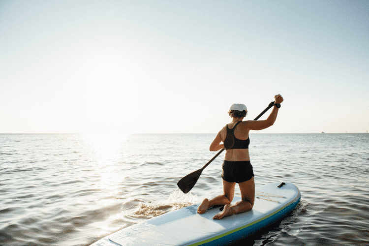 Angled back view of a woman paddle boarding
