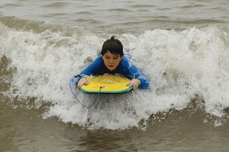 A child practicing bodyboard in the sea waves