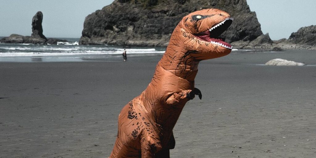 Dinosaur costume standing by the beach