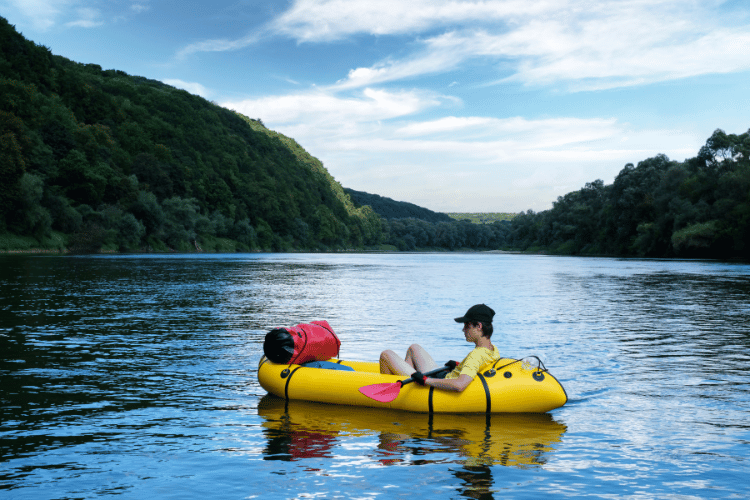 Tourist on yellow inflatable kayak boat with red padle
