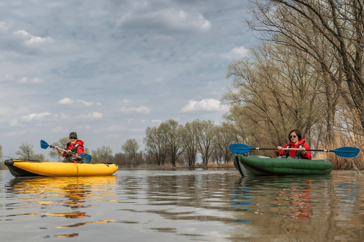 Two fisherwomen on inflatable boats with blue paddles