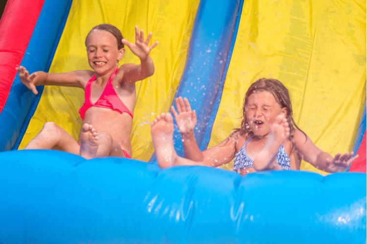 Two little girls having fun on an inflatable water slide