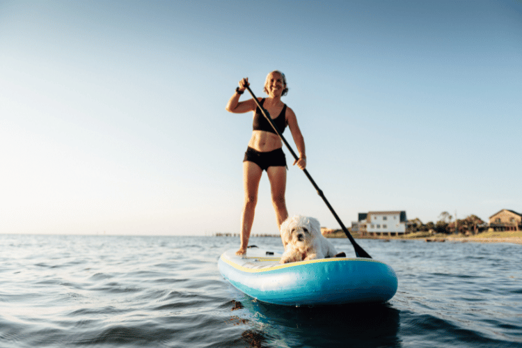 Woman Paddle Boarding with Maltese dog