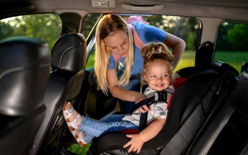 Woman putting child in car seat