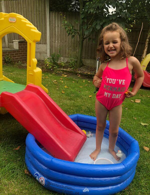 a girl playing on a small inflatable pool with slide