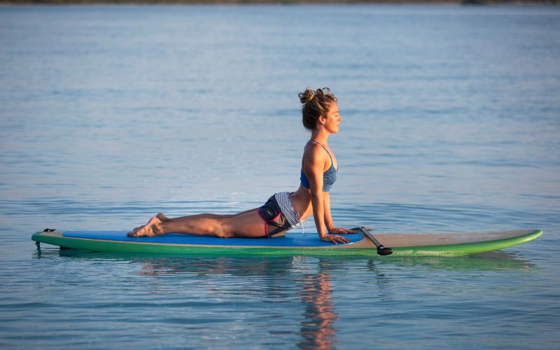 a woman doing yoga on inflatable paddle board