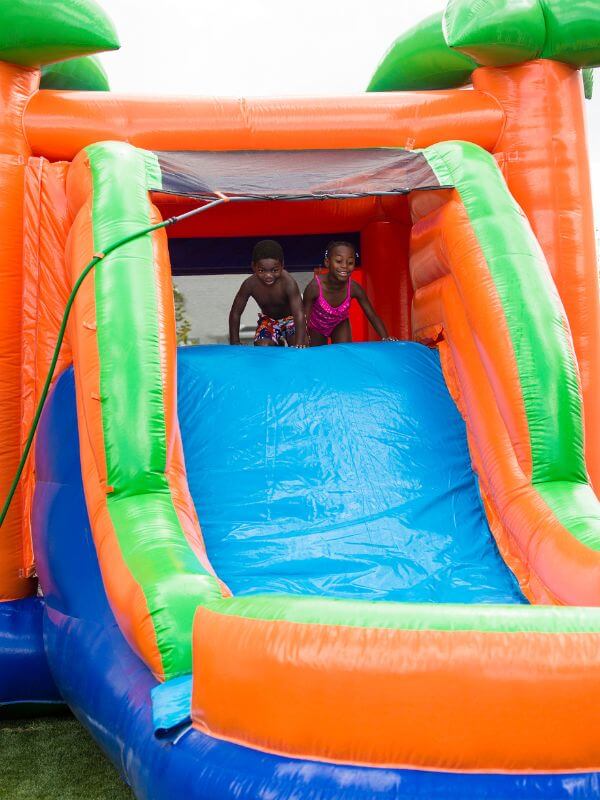 children playing on inflatable slide with water