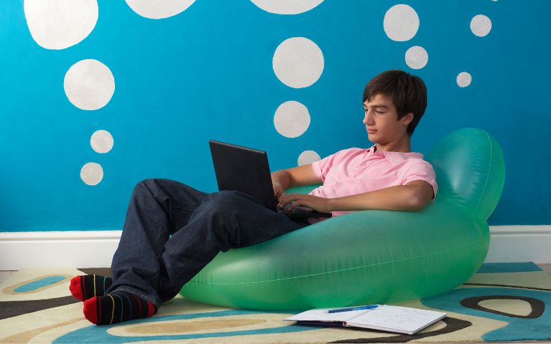 boy sitting on inflatable chair with laptop