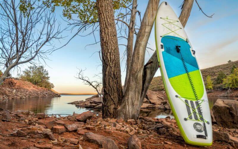 inflatable paddle board on a rocky shore of mountain lake 