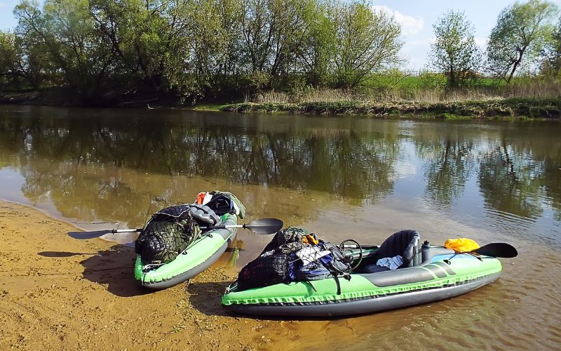 two green inflatable kayaks on the river